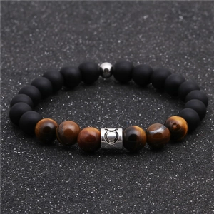 Close-up of matte black beads and tiger eye stones bracelet with Taurus zodiac charm