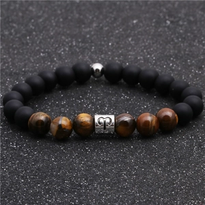 Macro detail of Aries zodiac charm on tiger eye and black matte beaded bracelet