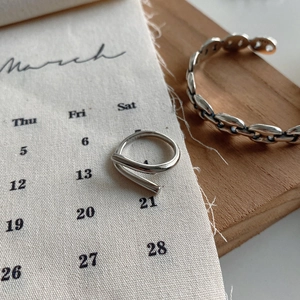 Detail of minimalist 925 sterling silver ring and link chain cuff bracelet on a tray