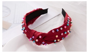 Close-up of a dark red knotted headband decorated with vibrant colorful pearls