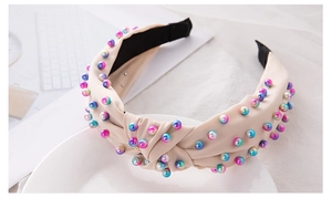 Close-up of beige knotted headband with colorful gradient beads on a lifestyle desk setting