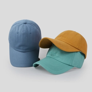 Detailed view of cotton baseball caps in blue, ginger yellow, and teal with curved brims