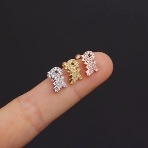 Three dinosaur stud earrings in gold, silver and rose gold with zircon stones on fingers