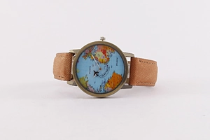 Macro detail of world map dial with airplane hands and bronze case on brown leather strap