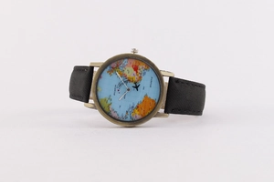 Detail of world map watch dial with mini world text and small plane icon in bronze