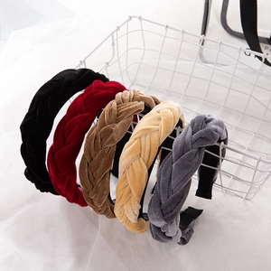 Braided velvet headbands in multiple colors displayed on a minimalist white wire basket