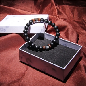 Macro detail of men's beaded bracelet with volcanic stone in a marble gift box