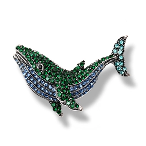 Vintage silver whale brooch with green crystals and blue rhinestones on white background
