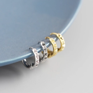 Close-up of S925 sterling silver and gold gear hoop earrings with tiny sparkling stones