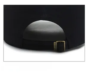 Détail d'une casquette de baseball noire montrant la sangle réglable et la boucle en bronze