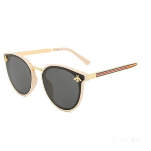 Detail of cream square sunglasses with gold bee motifs and striped temple design