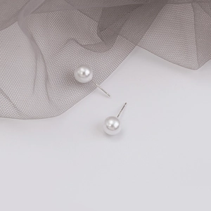 Close-up of minimalist round white pearl stud earrings with S925 sterling silver stamp