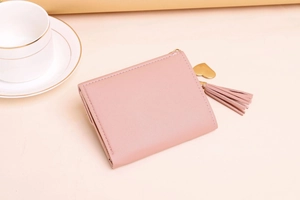 Pink trifold leather wallet detail with lychee texture and heart tassel zipper pull