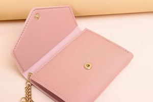Close-up of pink faux leather wallet with lychee texture and golden snap button