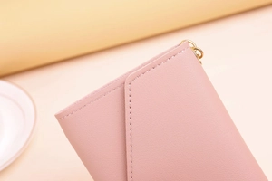 Close-up of pink faux leather wallet with premium stitching and golden metal ring detail