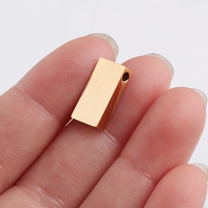 Close-up of a small polished golden rectangular bead pendant shown on a fingertip