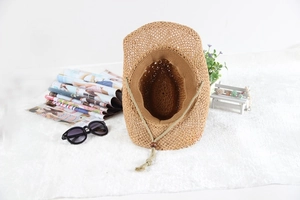 Detail view of khaki woven straw sun hat with adjustable cord and internal lining