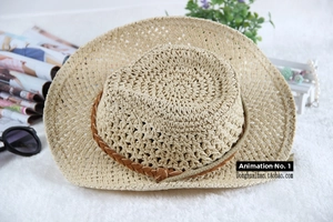 Detail of beige straw sun hat with breathable hollow weave and brown leather trim strap