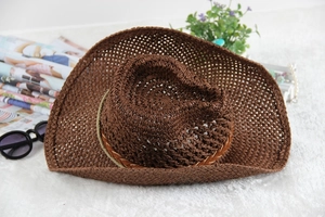 Detail of hollow woven dark brown straw cowboy hat with a wide brim on soft white rug