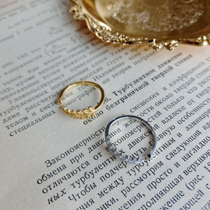 Detailed view of leaf-shaped gold and silver rings resting on a vintage book page