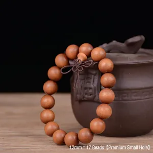 Close-up of 12mm dark brown sandalwood beads with natural wood grain and fine small holes