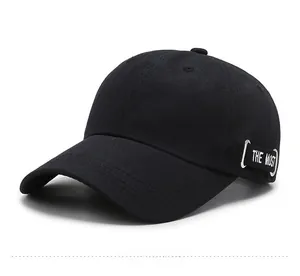 Détail d'une casquette noire en coton avec ruban THE MOST et anneau métallique argenté