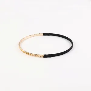 Detail of gold chain headband with black non-slip protective tips on a white background