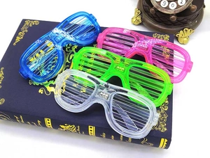 LED shutter glasses in blue, pink, green and clear displayed on a decorative book