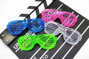 Detail shot of four LED shutter glasses in pink, blue, clear, and green on a movie slate