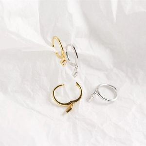 Macro shot of silver and gold geometric rhombic diamond huggie earrings on white tissue