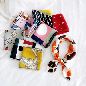 Flat lay of multiple printed silk square scarves with floral and cat patterns