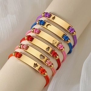 Detail showing 18K gold plated rectangular plates with hollow charms on braided cords