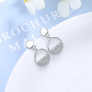 Elegant silver circle earrings with paved cubic zirconia on a minimalist white ceramic tray