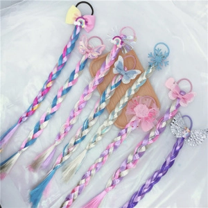 Glitter rainbow braided hair extensions with bow and butterfly clips on wooden tray