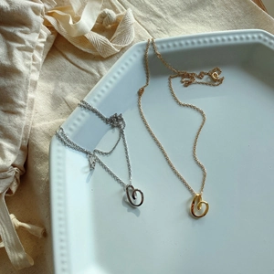 Collane con pendente a cuore in oro e argento su vassoio in ceramica bianca e sacchetto