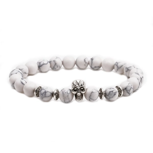Detailed macro view of white howlite stone beads with silver skull charm on elastic bracelet