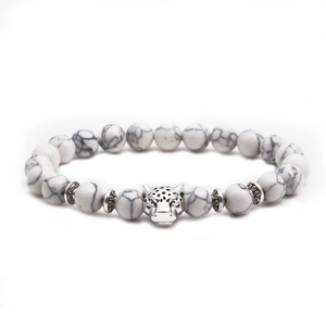 Detail view of white turquoise beaded bracelet featuring a silver leopard head charm