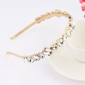 Close-up of luxury gold headband with sparkling crystal rhinestones on a white cup