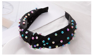Detail of black fabric knotted headband featuring vibrant multi-color faux pearls