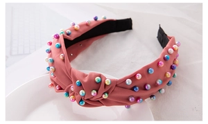 Detailed close-up of pink knotted headband decorated with colorful imitation pearls