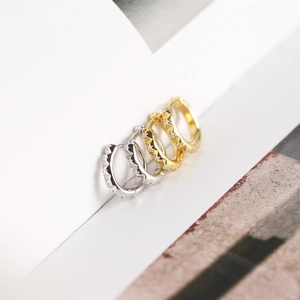 Detail of silver and gold gear-shaped huggie earrings with sparkling inlaid zircons