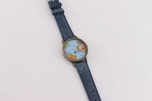 Detail of world map dial and bronze case on watch with navy blue denim strap