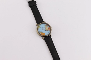 Detail of world map watch face with bronze case and black leather strap on white background