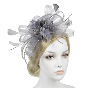 Detail of grey feather fascinator with mesh veil and pearls on golden hair model