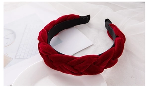 Close-up of red velvet braided headband with intricate twisted texture and fabric lining
