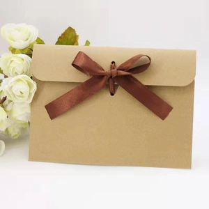 Detail of kraft paper envelope with decorative brown silk ribbon bow and floral accent