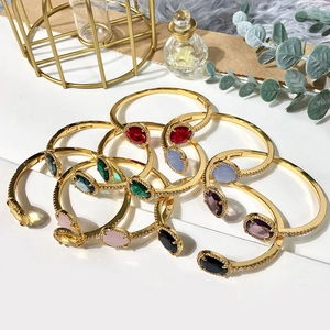 Close-up of stacked colorful gemstone open bracelets in gold finish for women