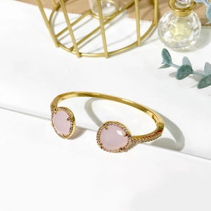 Detail of gold open bangle with pink faceted gemstones and white zircon accents
