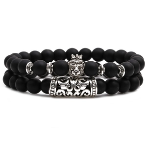 Detail of matte black beaded bracelets with silver lion head and crown charm ornaments