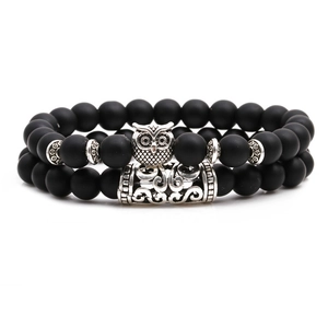 Matte black agate beaded bracelet set with silver owl charm and metal tube on white background